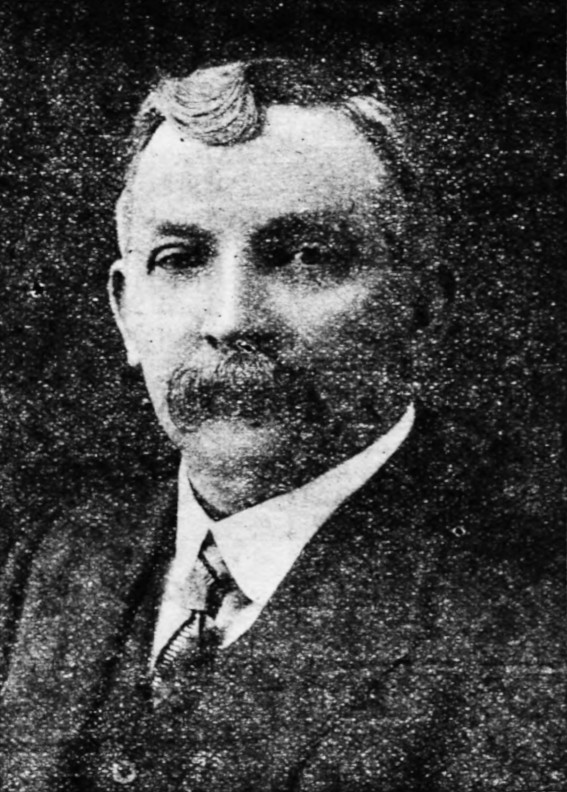 A newspaper black-and-white photograph of Gwilym Lewis, a man in his late 40s with a moustache, wearing a dark jacket, light shirt and a tie.